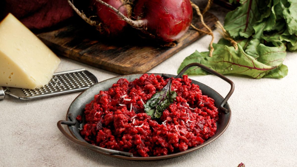 Schnelles Rote-Bete-Risotto in schwarzer Pfanne, dahinter Parmesan und Gemüse