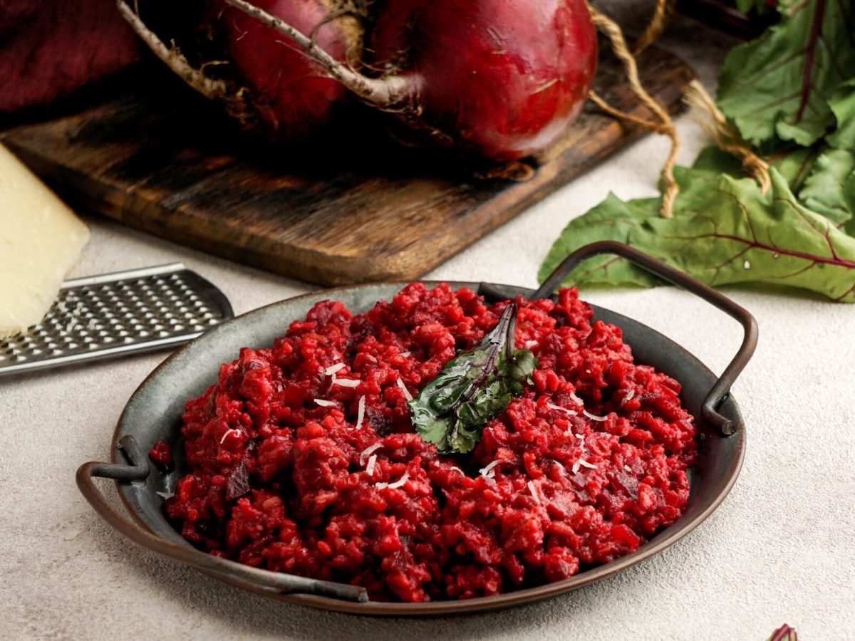 Schnelles Rote-Bete-Risotto in schwarzer Pfanne, dahinter Parmesan und Gemüse