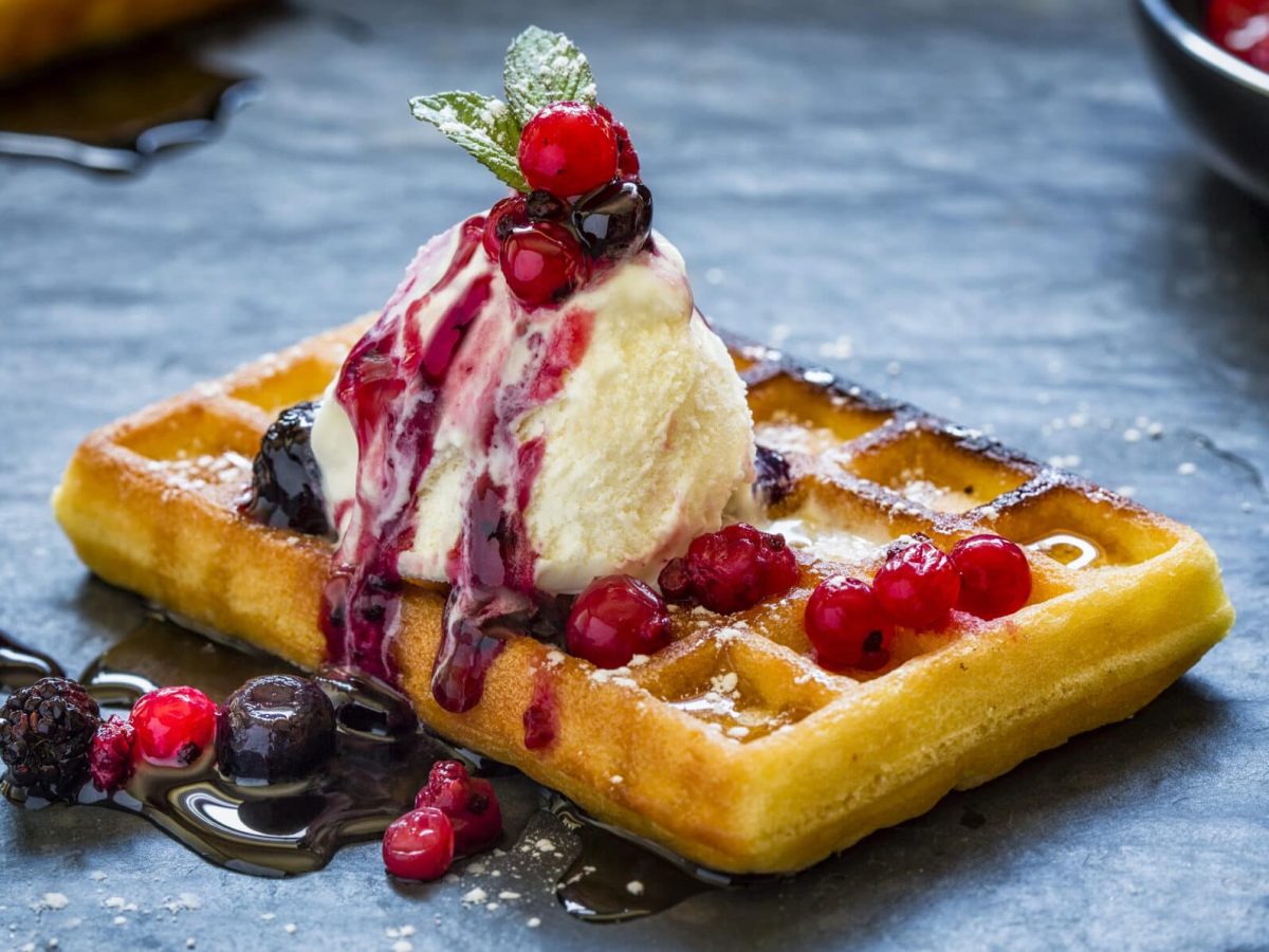 Saftige Waffeln mit Honig-Eis vor blauem Hintergrund