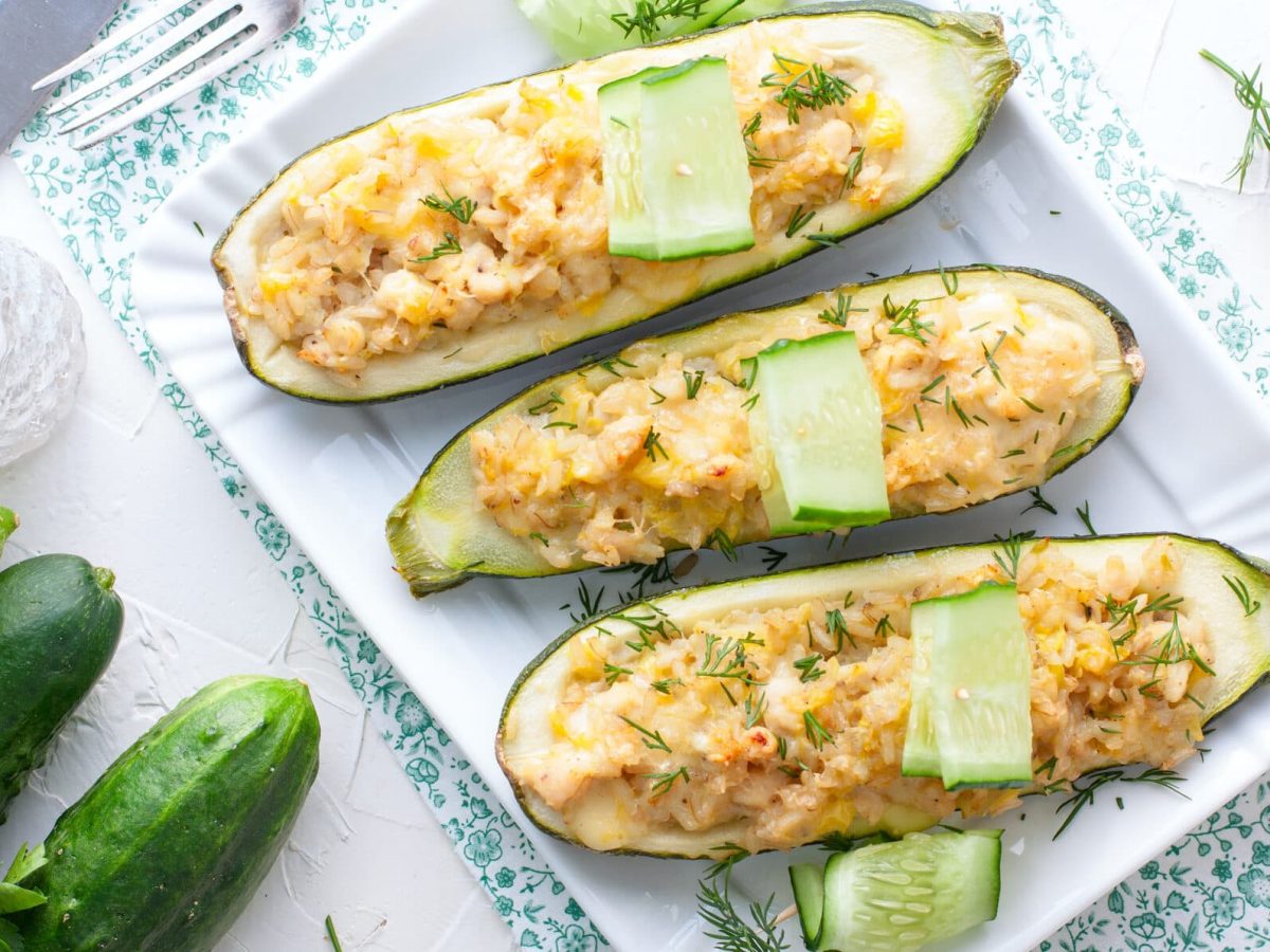 Gefüllte Zucchini mit Hähnchen-Risotto auf weißem Teller, daneben Zucchini