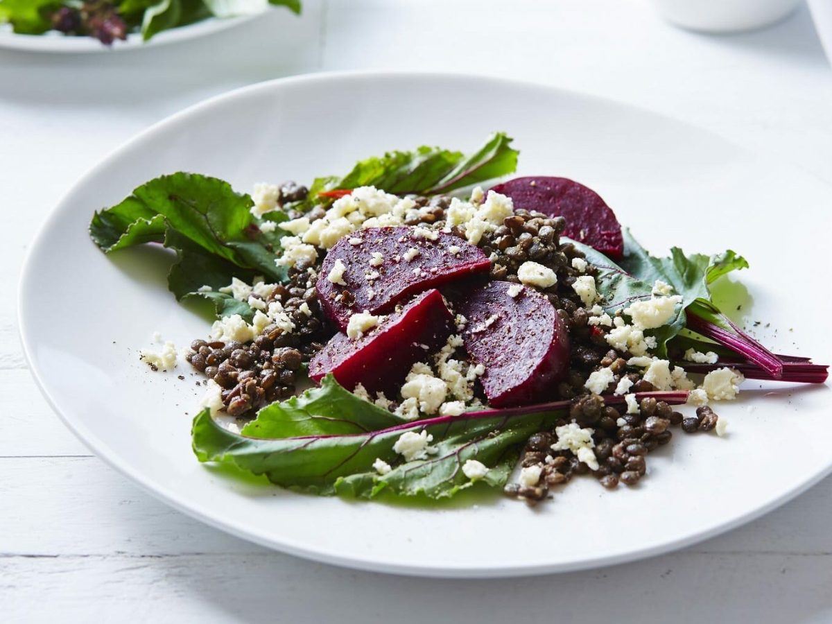 Linsensalat mit Rote Bete und Feta auf weißem teller auf einer weißen Holztischplatte