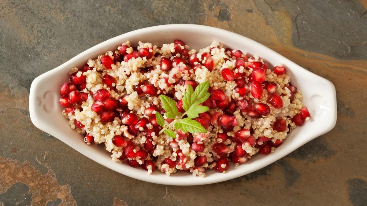 Eine weiße Schüssel mit Quinoa-Salat mit Granatapfel.