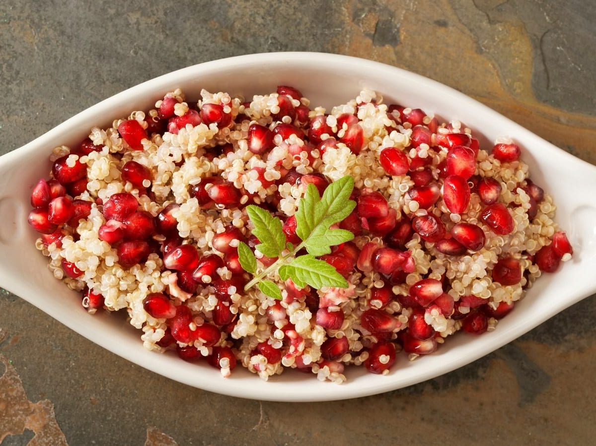 Eine weiße Schüssel mit Quinoa-Salat mit Granatapfel.