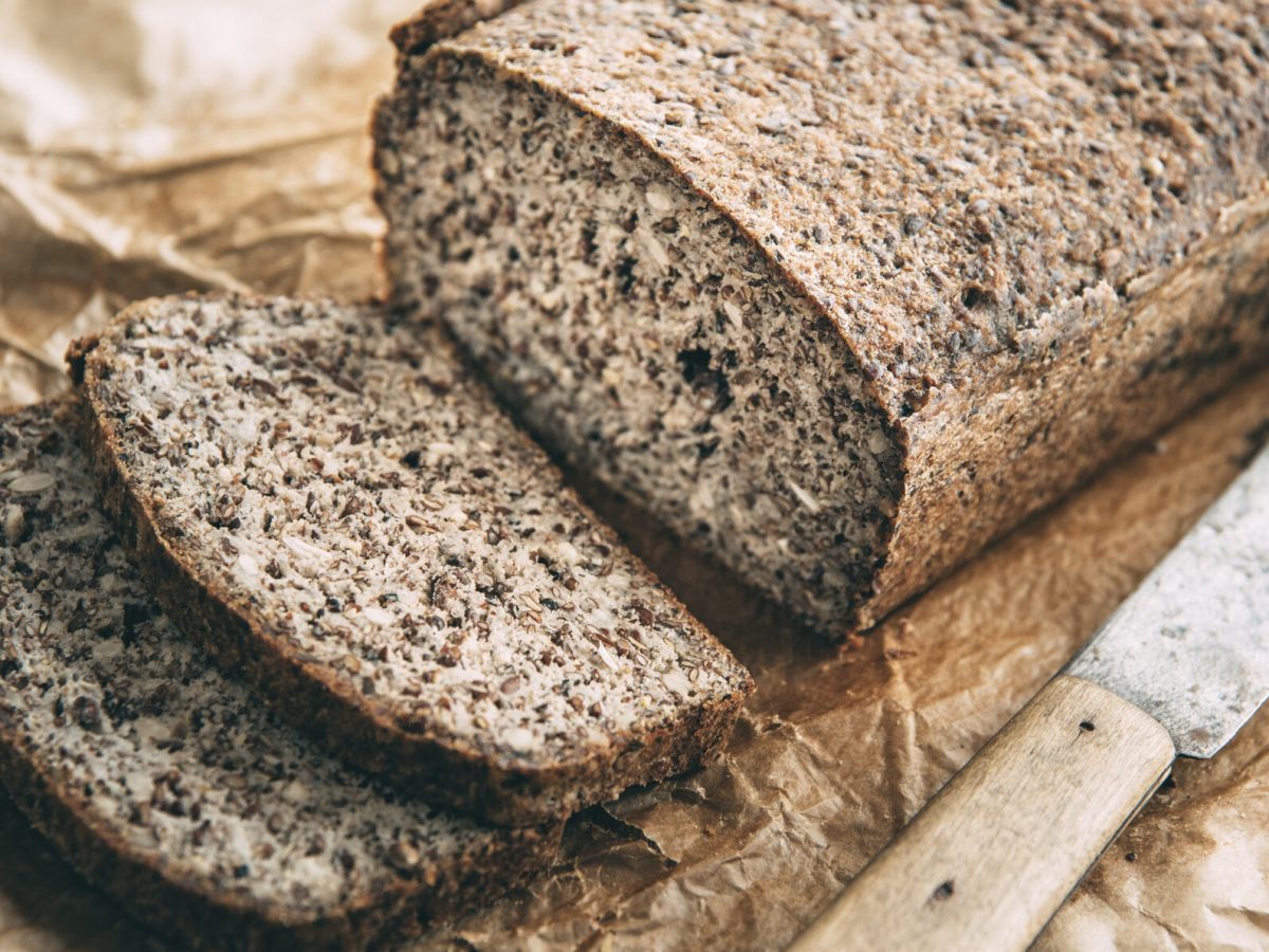 Glutenfreies Chia-Brot mit Quark, daneben Messer auf Holzbrett