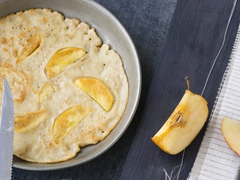 Schnelle Pfannkuchen mit Apfel in Pfanne, daneben Apfel