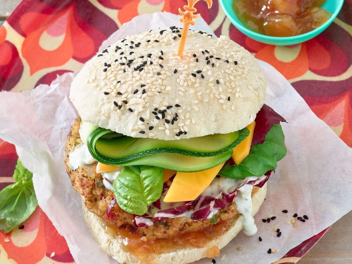 Veganer Burger mit Kichererbsen-Patty auf Papierunterlage und rotem Tablett