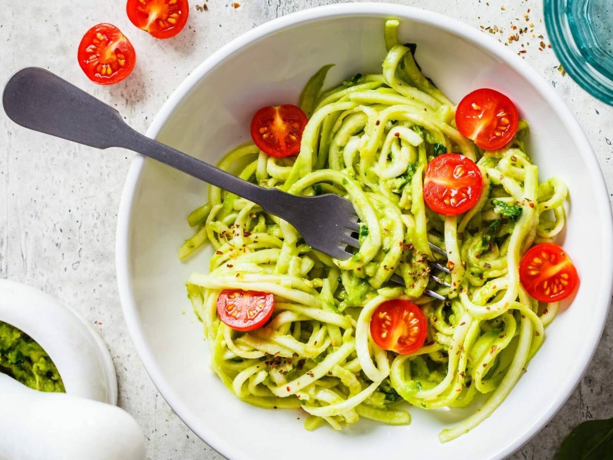 Zucchini-Nudeln mit selbst gemachtem Pesto in weißer Schüssel, daneben Pesto