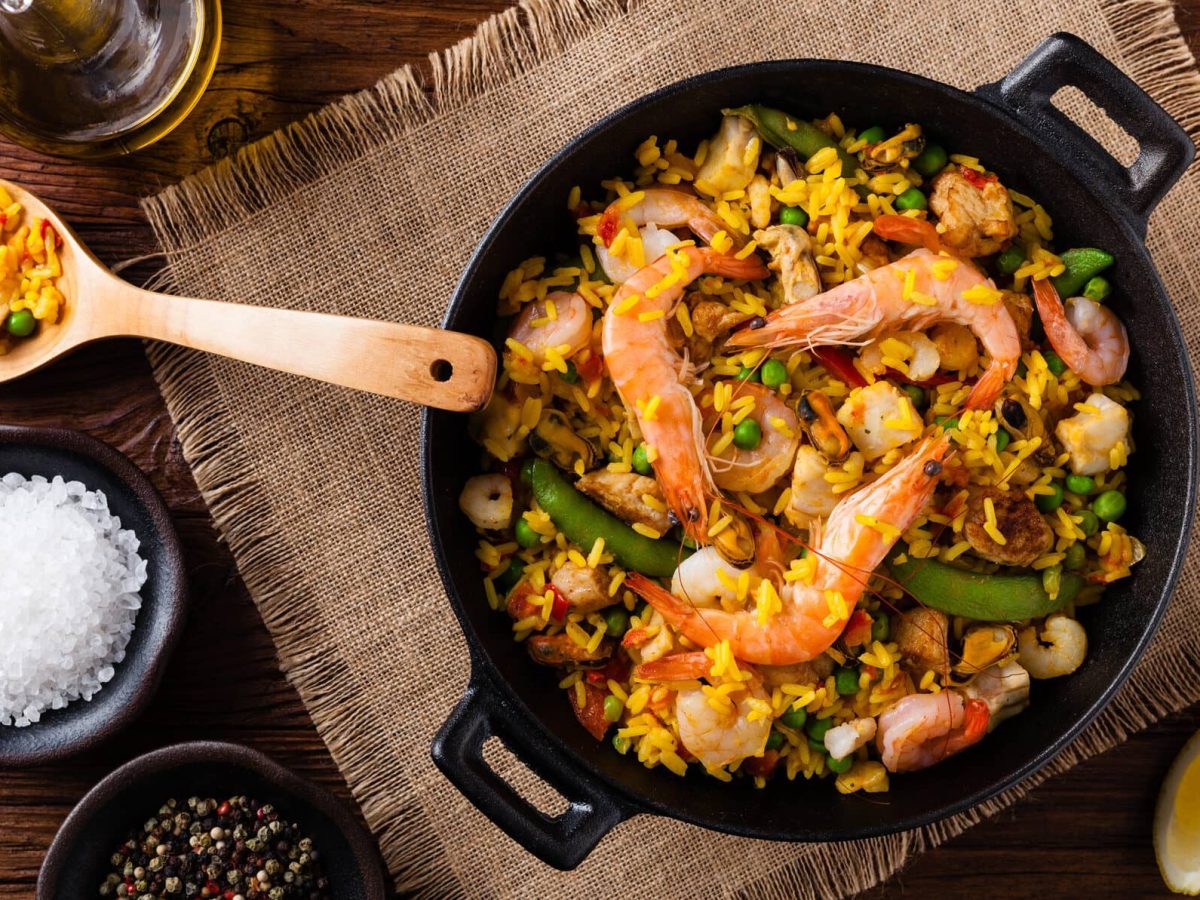 Paella mit Meeresfrüchten und Hähnchen in Pfanne auf Tuch