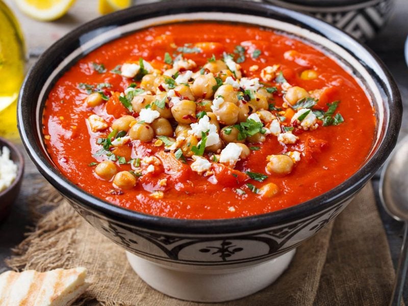 Tomatensuppe mit Quinoa und Hüttenkäe in schwarz-weißer Schüssel auf Holzuntergrund