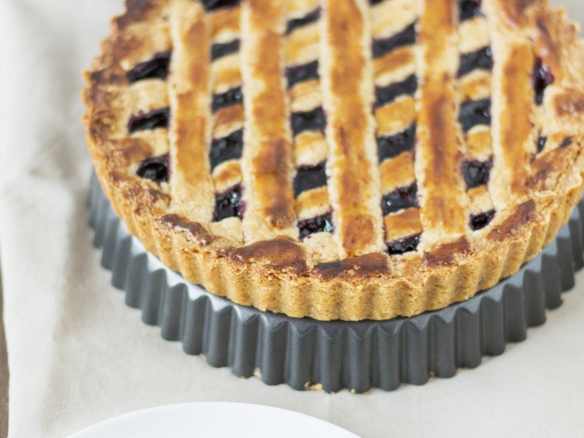 Saftige und nussige Linzertorte mit Johannisbeerfüllung und schönem Gittermuster auf hellem Untergrund.