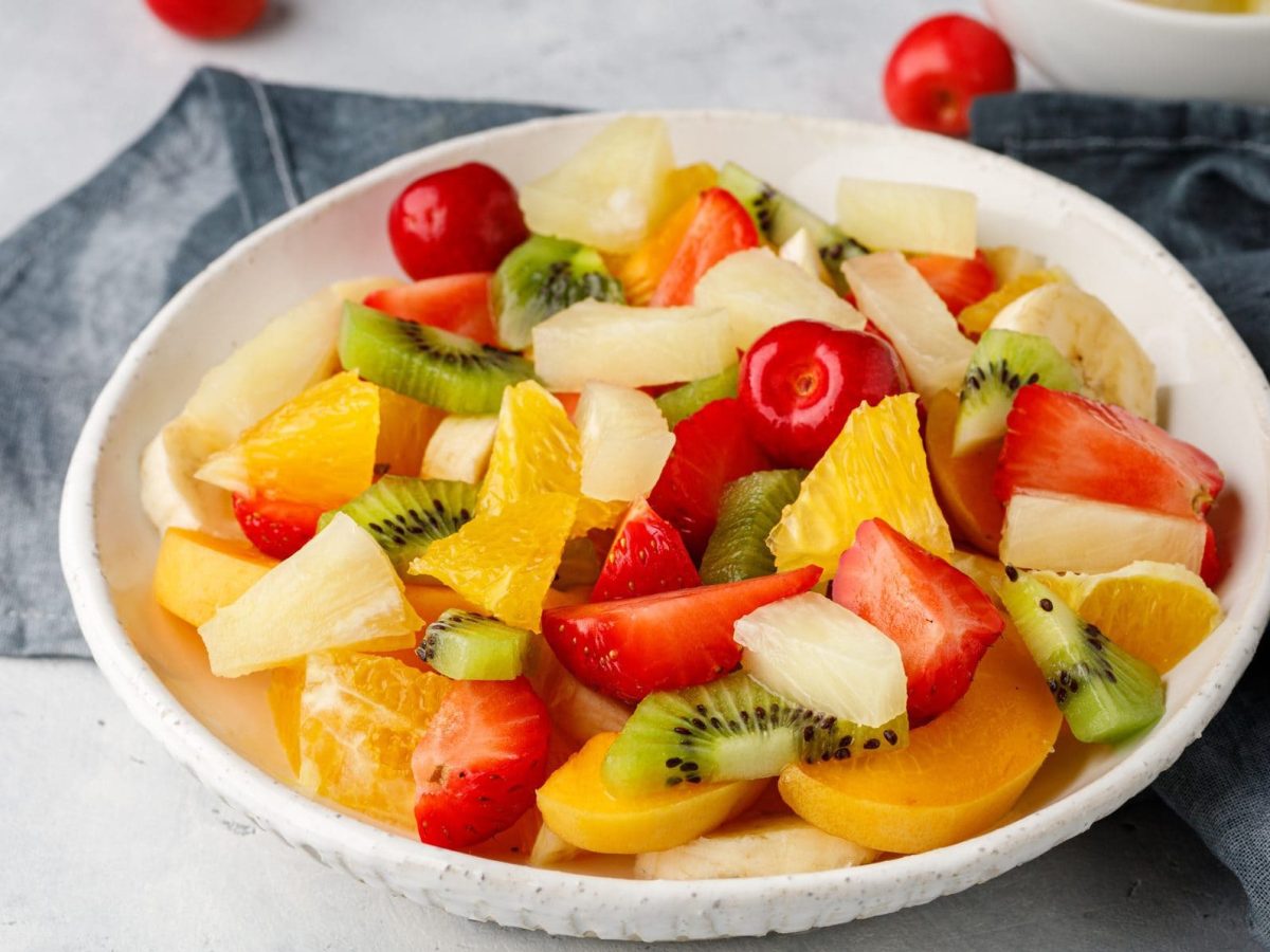 Einfacher Obstsalat mit Vanille in Schüssel, daneben graues Küchenhandtuch