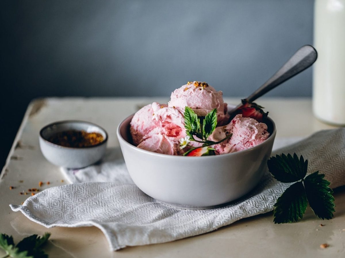 Erdbeer Frozen Yoghurt in weißer Keramikschale auf Holztisch