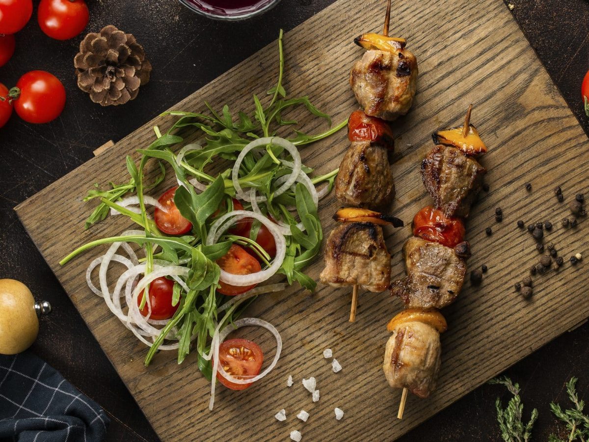 Holzbrett mit würzigen Steak-Spieße mit Rucola-Salat