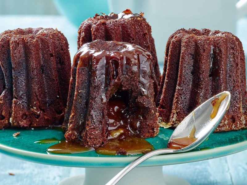 Canelés mit flüssigem Karamellkern auf blauer Kuchenplatte