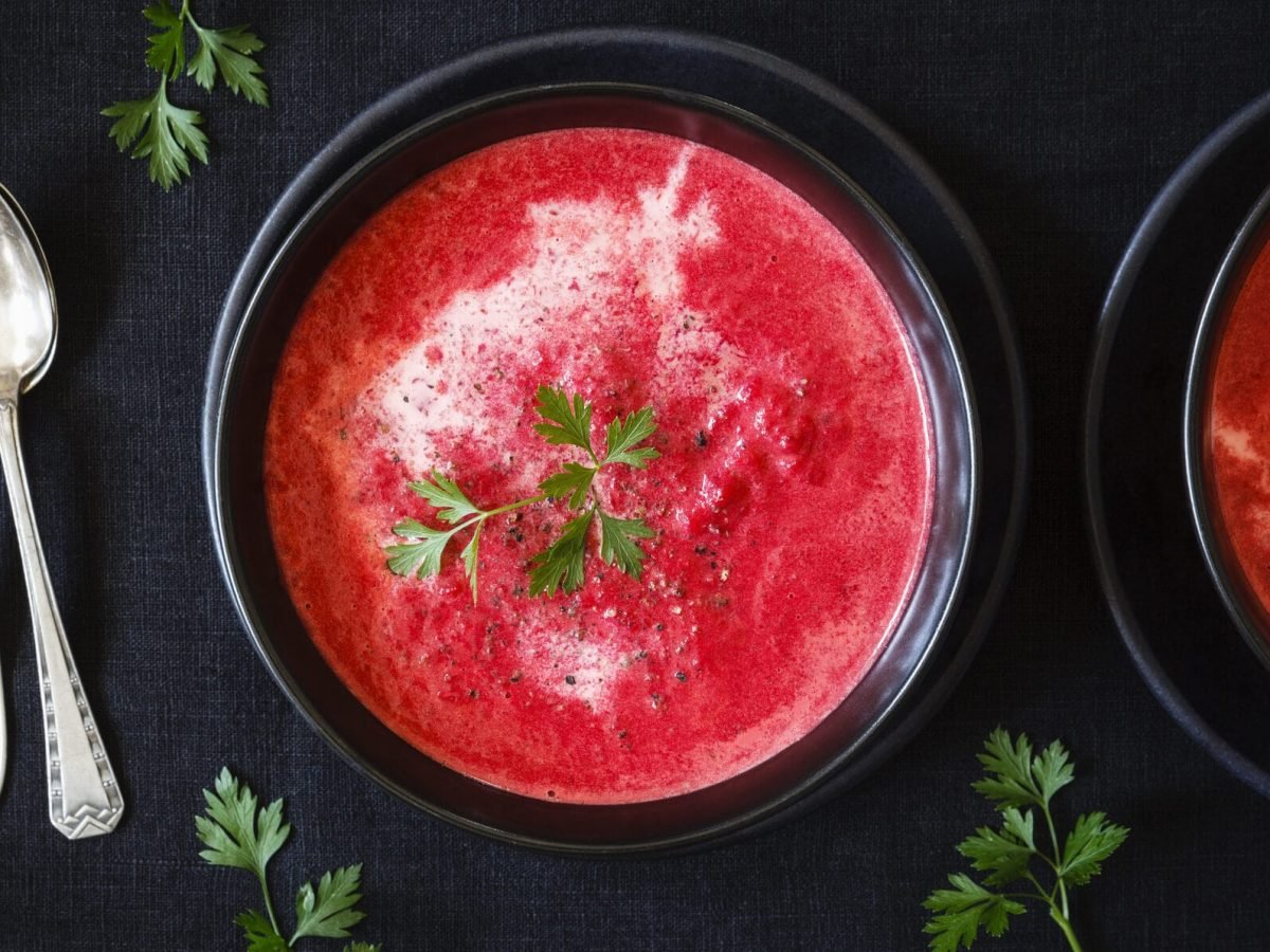 Süße Gazpacho mit Wassermelonen in schwarzen Schalen vor schwarzem Hintergrund