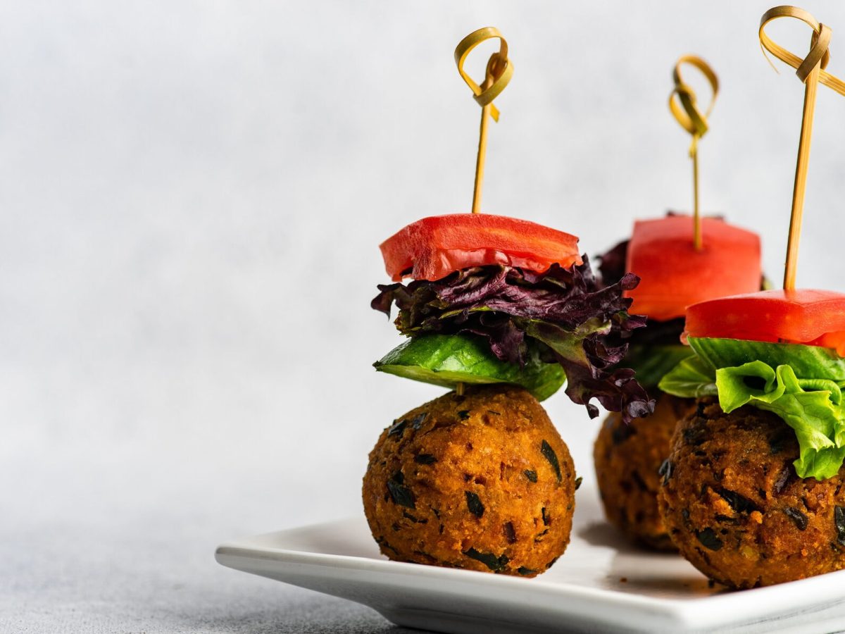 Spieße mit Kürbis-Falafel auf weißem Teller vor hellem Hintergrund