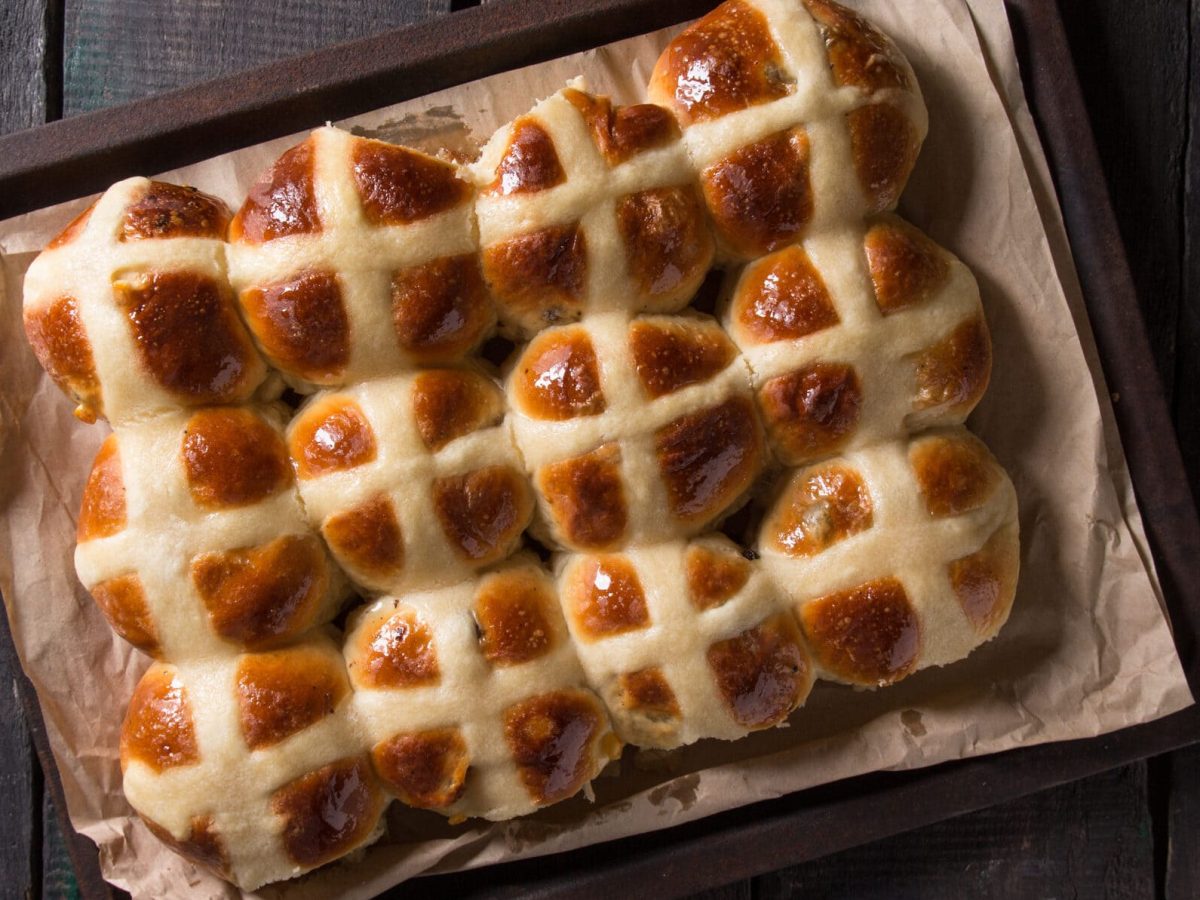 Fluffige Hot Cross Buns mit Aprikosenkonfitüre auf Blech mit Backpapier