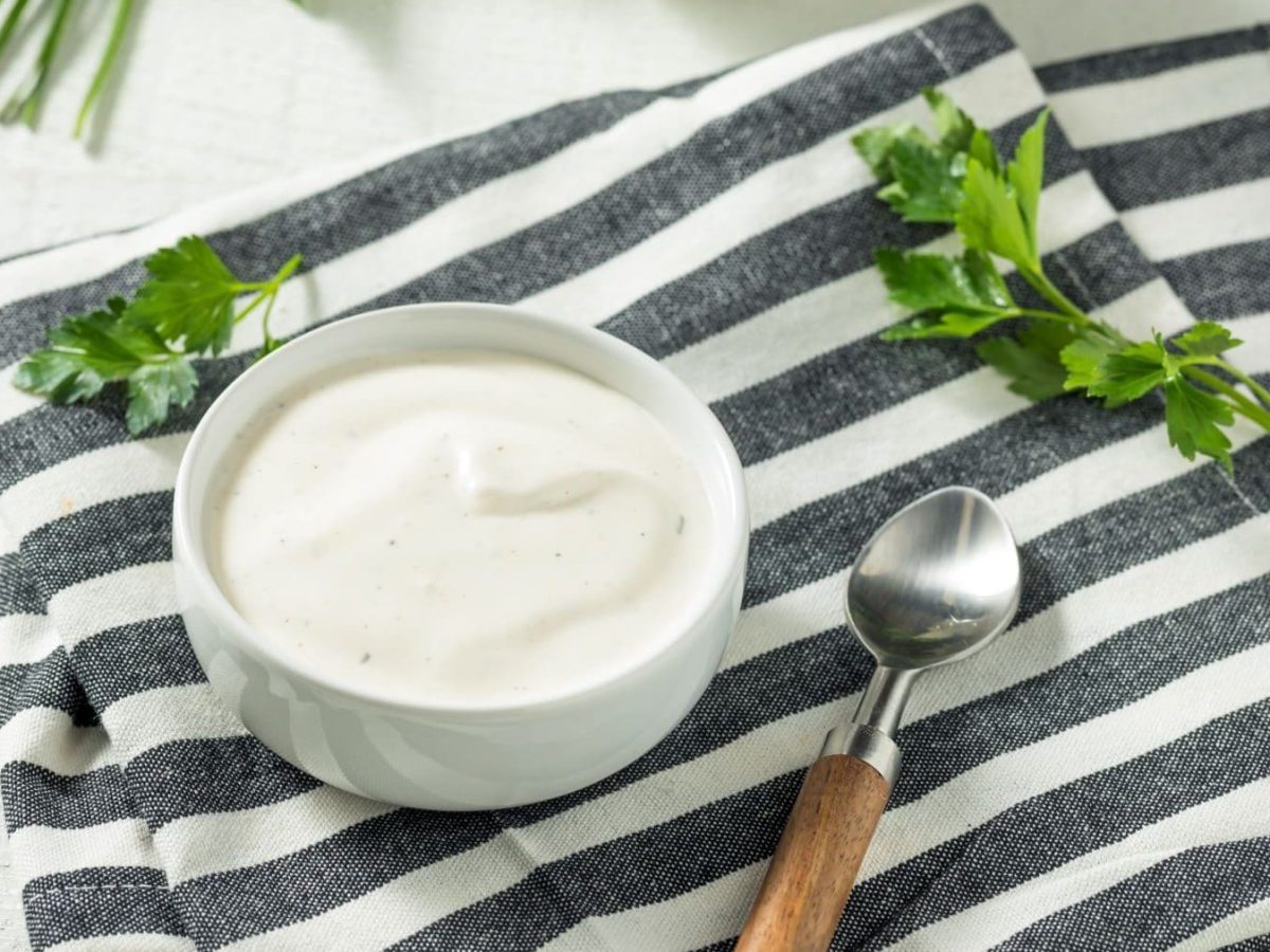 Ranch-Dressing auf gestreiftem Tuch mit Petersilie und einem Löffel