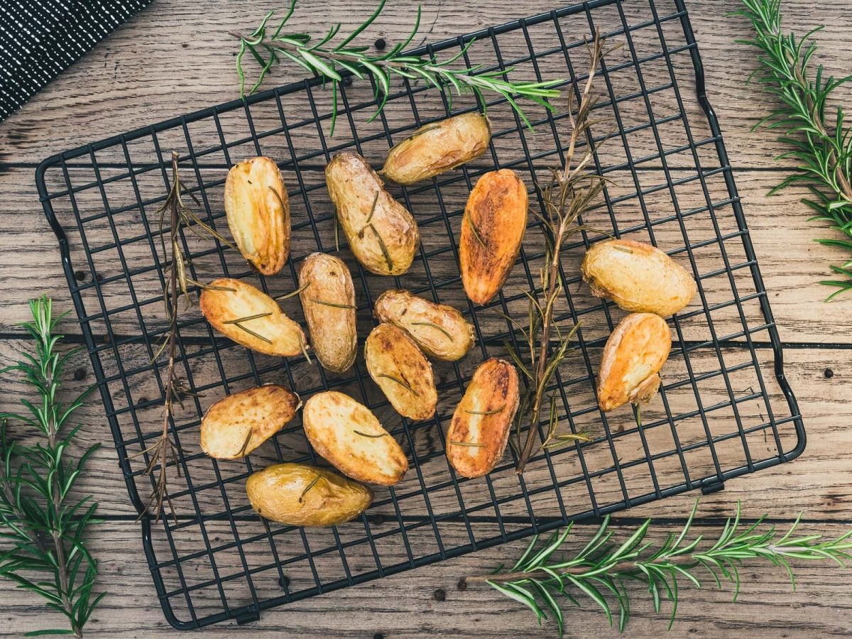 Knusprige Ofenkartoffeln auf Gitter mit Rosmarin.