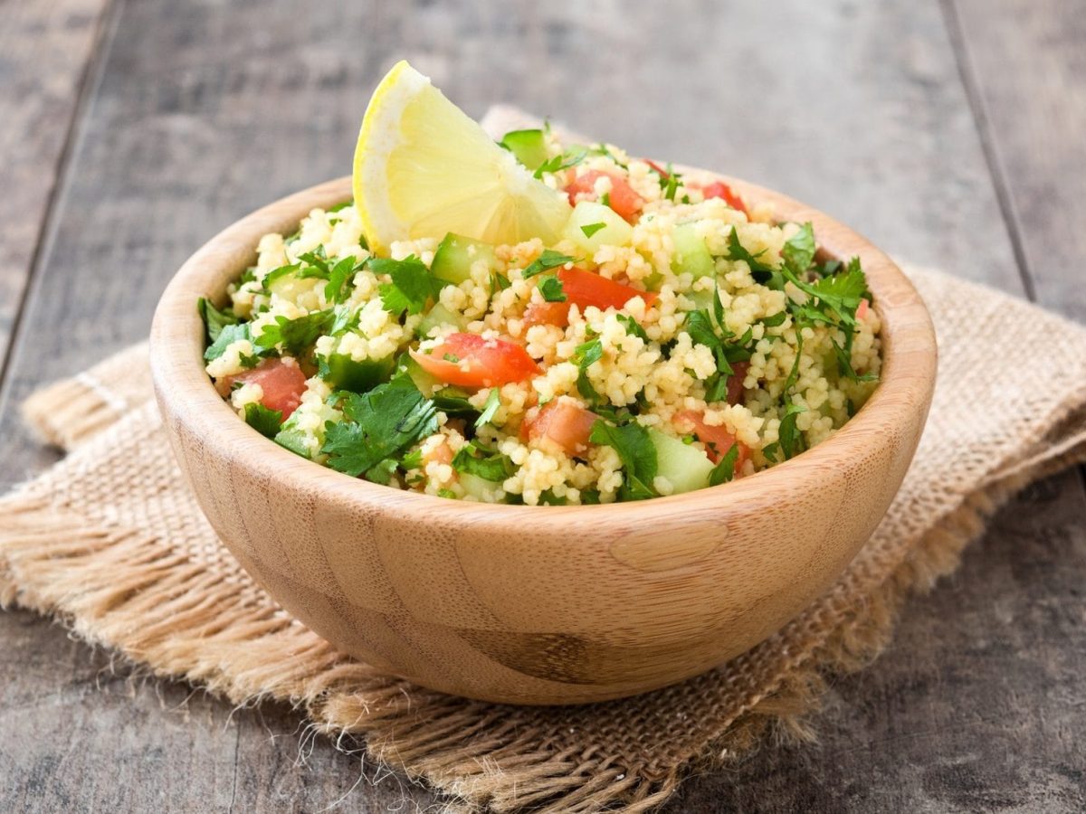 Bulgur-Tomatensalat mit Petersilie in einer Holzsschale auf einem Holztisch