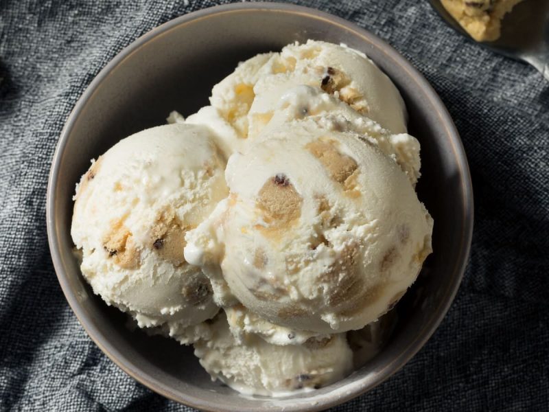 Vier Bällchen Cookie-Dough-Eis in einer Schüssel vor grauem Hintergrund, von oben fotografiert