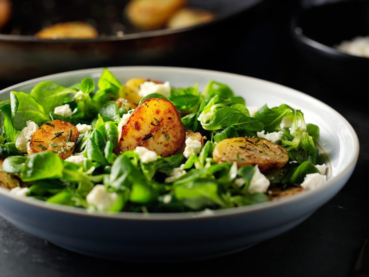 Feldsalat mit Röstkartoffeln und Feta in einer Schale.