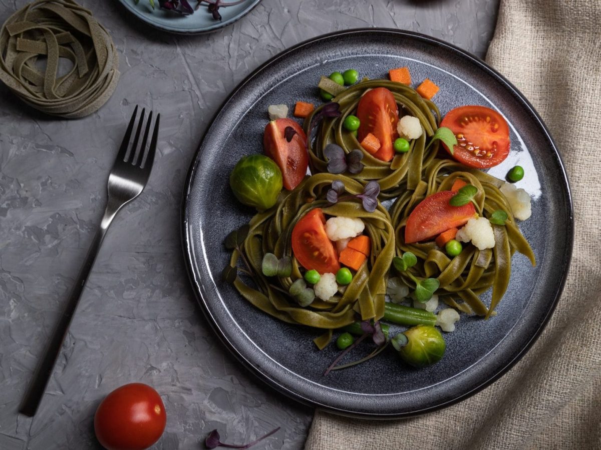 Tagliatelle-Gemüse-Nester aus dem Ofen mit Tomaten, Rosenkohl, Blumenkohl, Möhren und Erbsen.