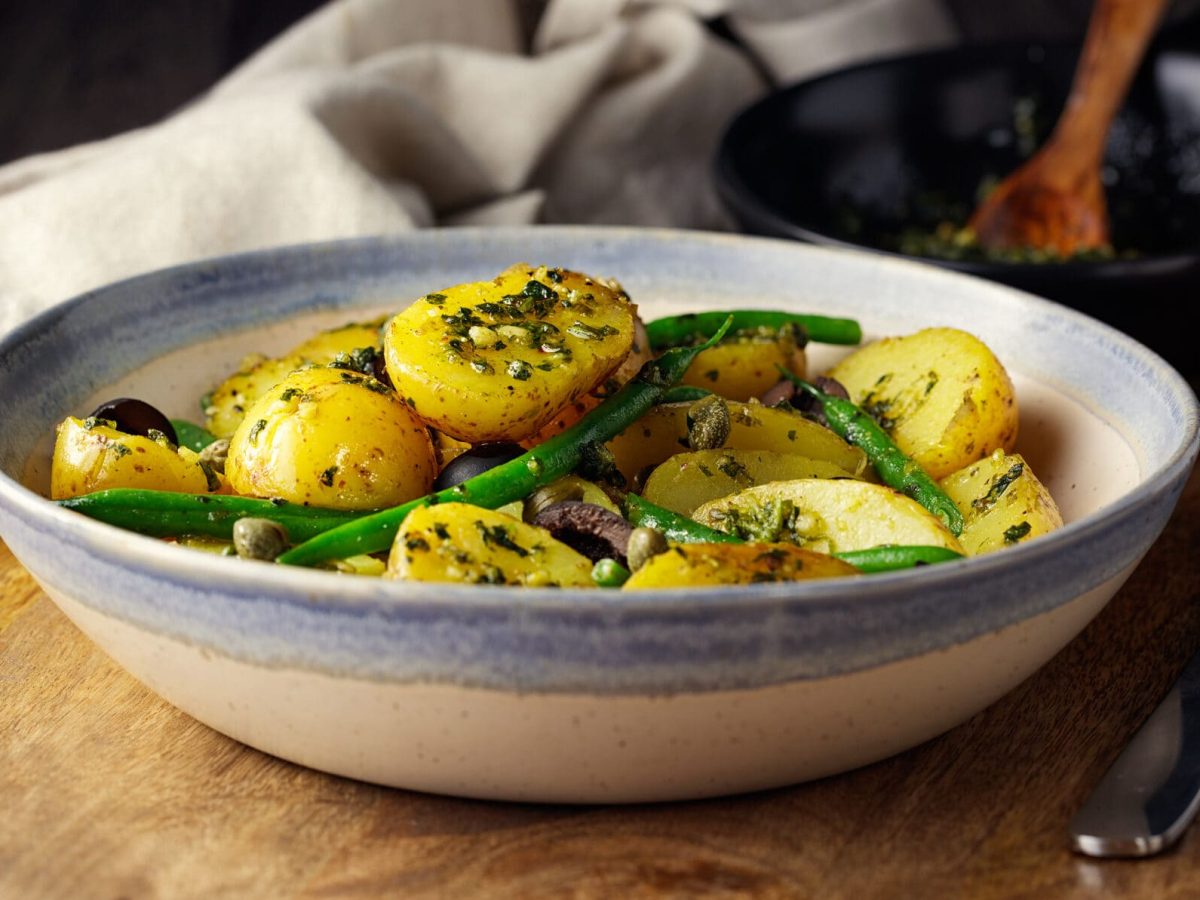 Schüssel mit Kartoffel-Spargelsalat, daneben grüner Spargel und Radieschen