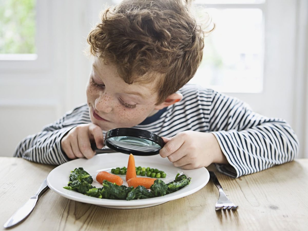 Junge betrachtet sein Essen durch eine Lupe