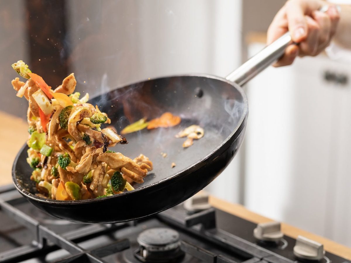 Thai-Pfanne mit Rindfleisch wird über Herd geschwenkt