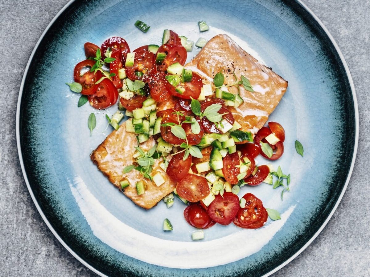 Lachs mit Gurken-Tomaten-Salat auf blauem Teller