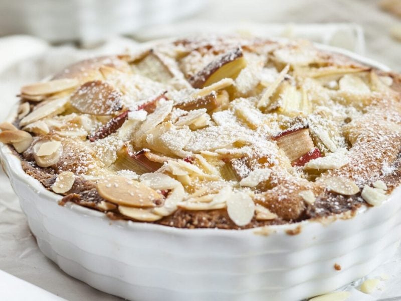 Ein Rhabarberkuchen mit Eierlikör und Mandeln in einer weißen Kuchenform