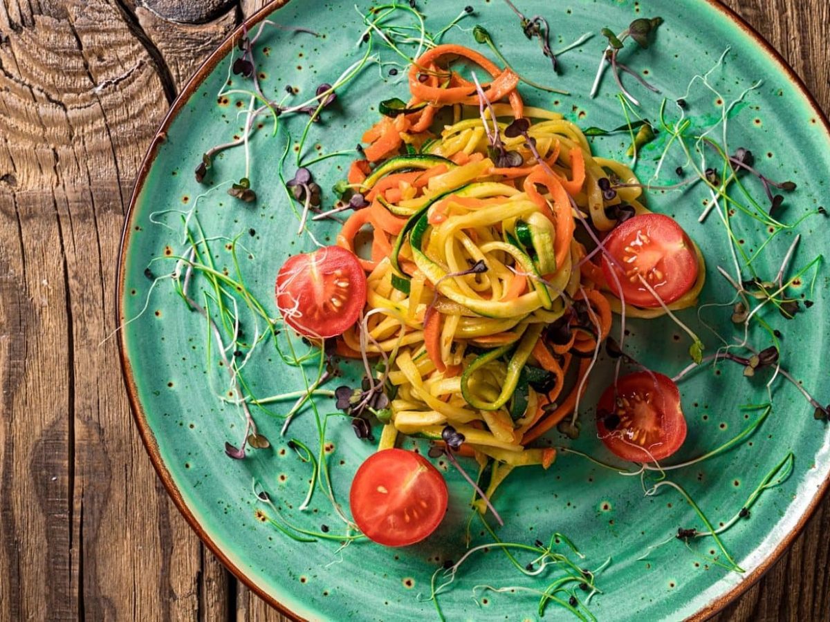 Spaghetti mit Zucchini und Möhren, dekoriert mit Kresse und Tomatenhälften.