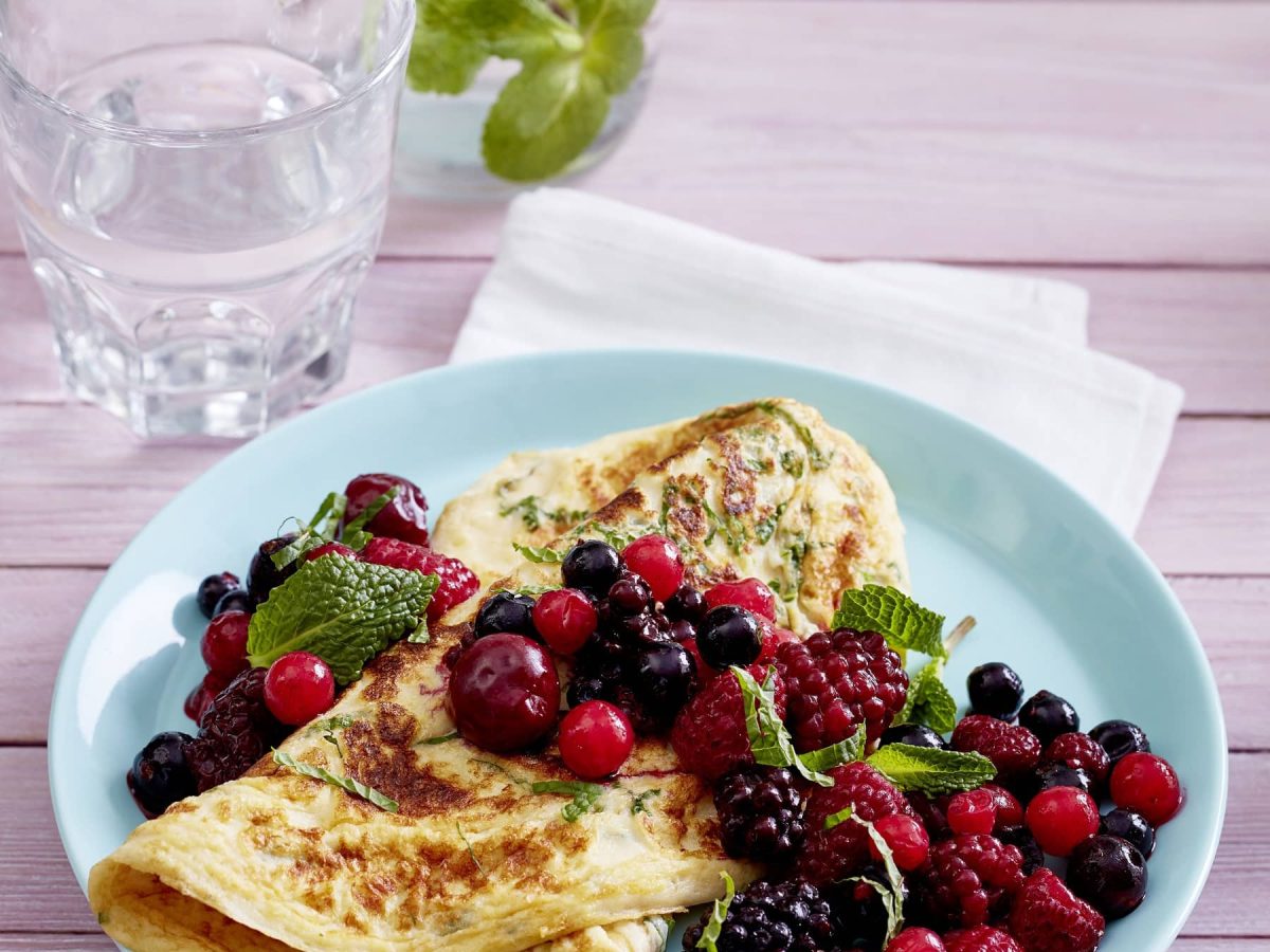 Pfannkuchen mit Minze auf blauem Teller mit Beeren