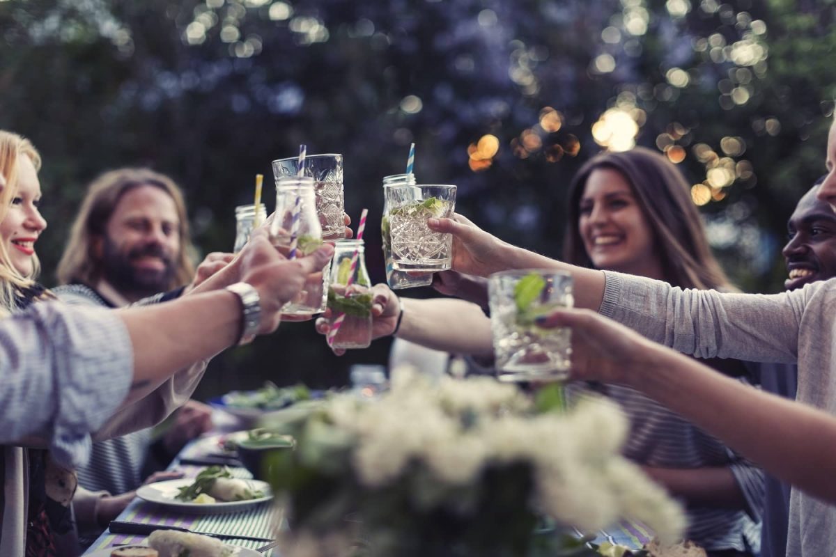 Drinkify: Freunde sitzen um einen Tisch und stoßen gemeinsam an