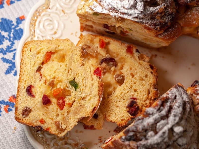 Der traditionelle Kuchen Torcolo aus Umbrien aufgeschnitten mit zwei Stücken, deren Inneres mit kandieren Früchten man sehen kann, auf einem verzierten Teller von oben.