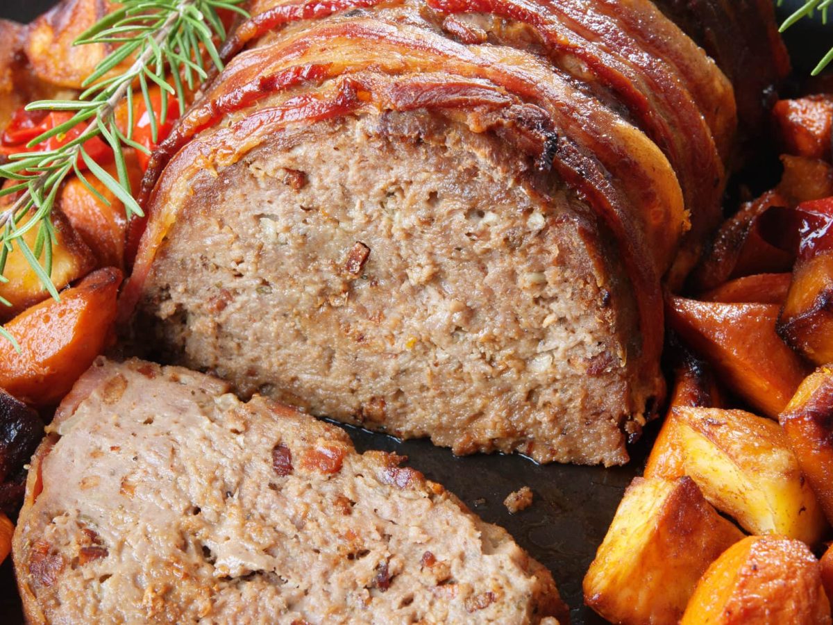 Hackbraten mit gerösteten Kartoffel- und Kürbisspalten angerichtet auf einem Teller.