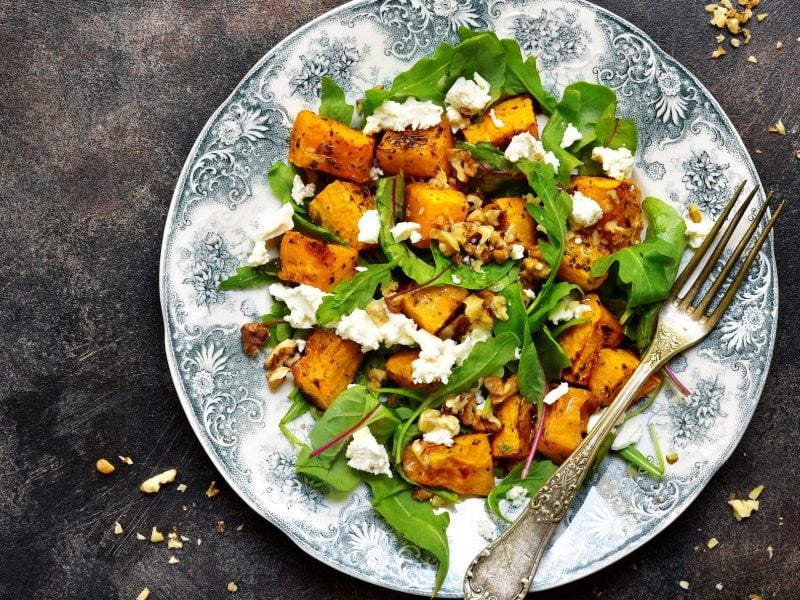 Salat aus Rucola, Kürbis, Feta und Walnuss auf verspieltem Teller