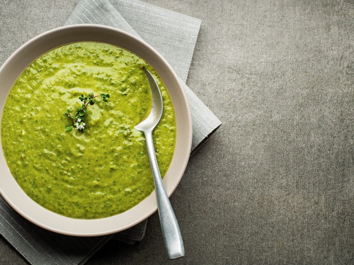 Grüne Suppe auf weißem Teller.