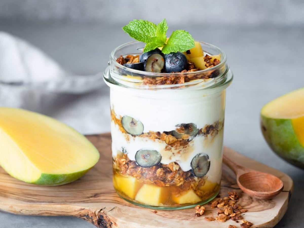 Knuspriges Granola mit Nüssen, Beeren und Mango in einem Glas.