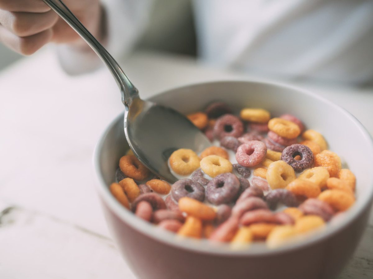 Eine Schale mit Milch und bunten Cornflakes, die als ungesunde Kinderlebensmittel gelten.