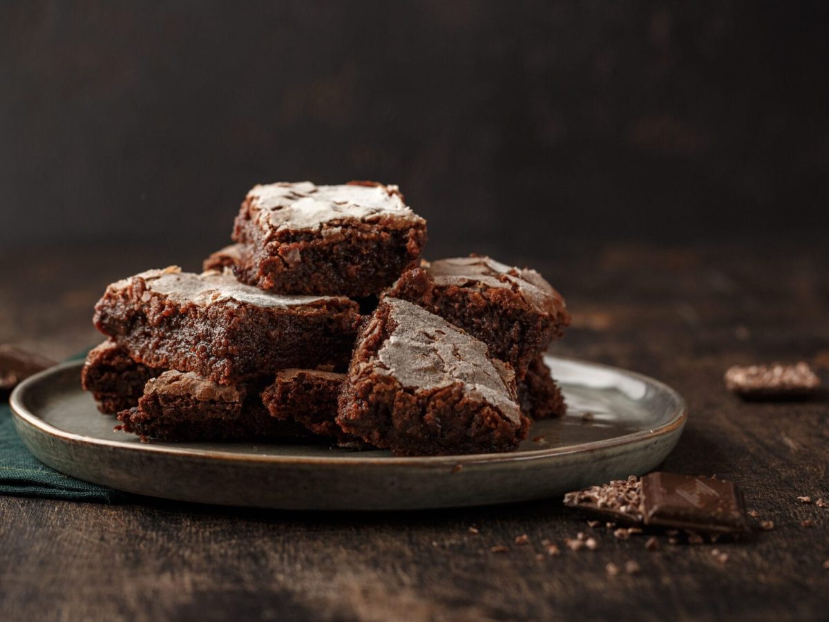 Mehrere Zucchini-Brownies liegen gestapelt auf einem Teller.