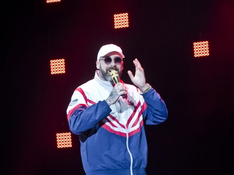 Rapper Sido mit Trainingsanzug, Kappe, Sonnenbrille und Mikrofon in der Hand auf der Bühne.