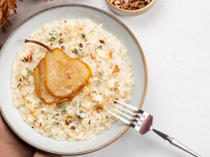 Risotto mit Gorgonzola und karamellisierter Birne auf Teller angerichtet.