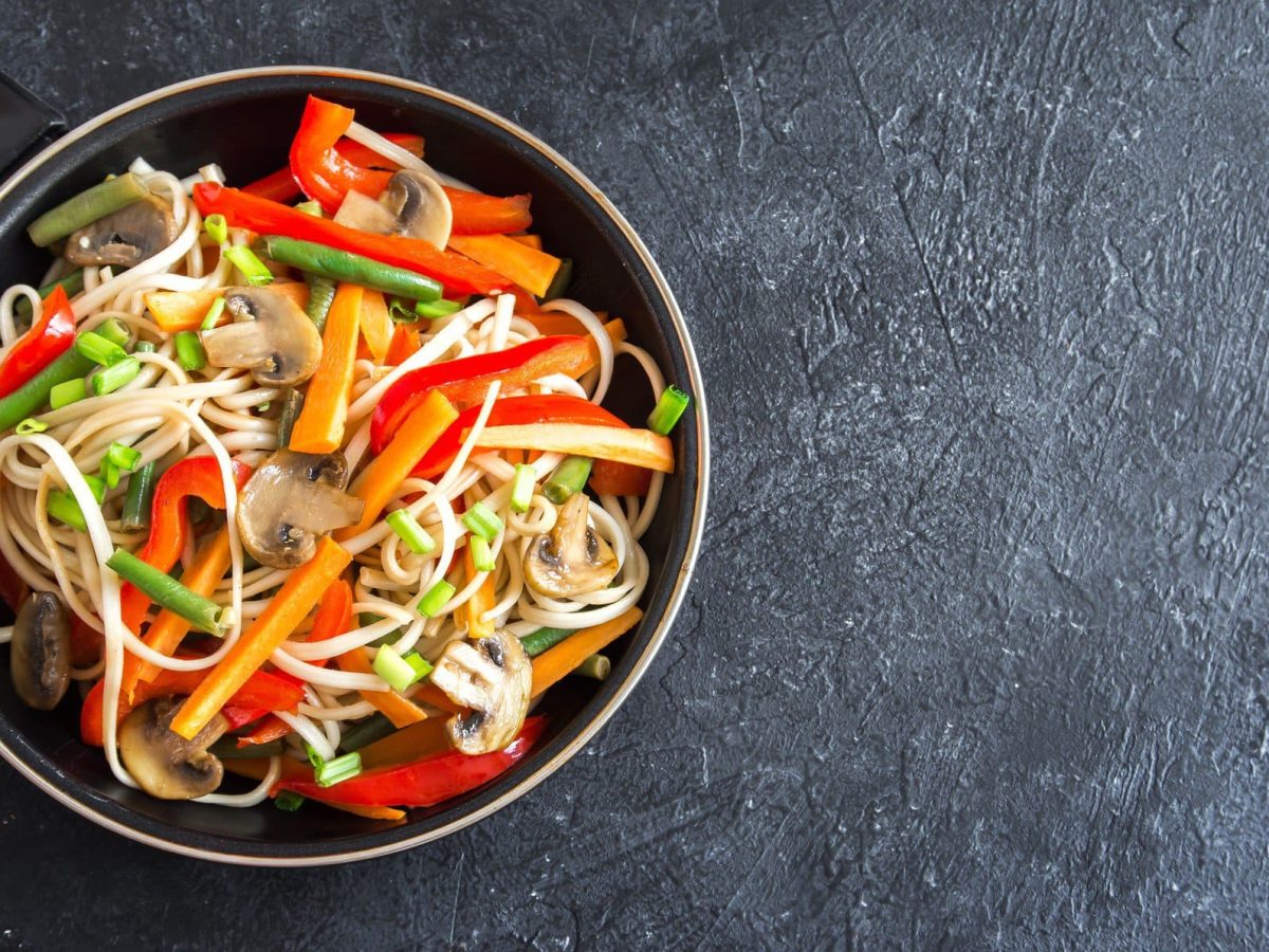 Eine Pfanne mit asiatischem Nudelsalat mit Möhren, Paprika, Bohnen und Pilzen