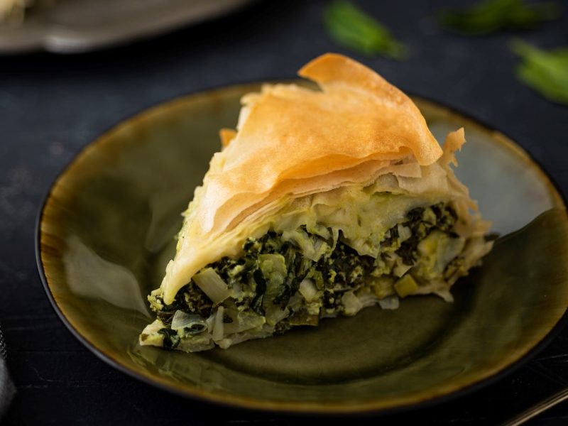 Ein Teller, auf dem ein Stück Börek mit Mangold und Schafskäse liegt.