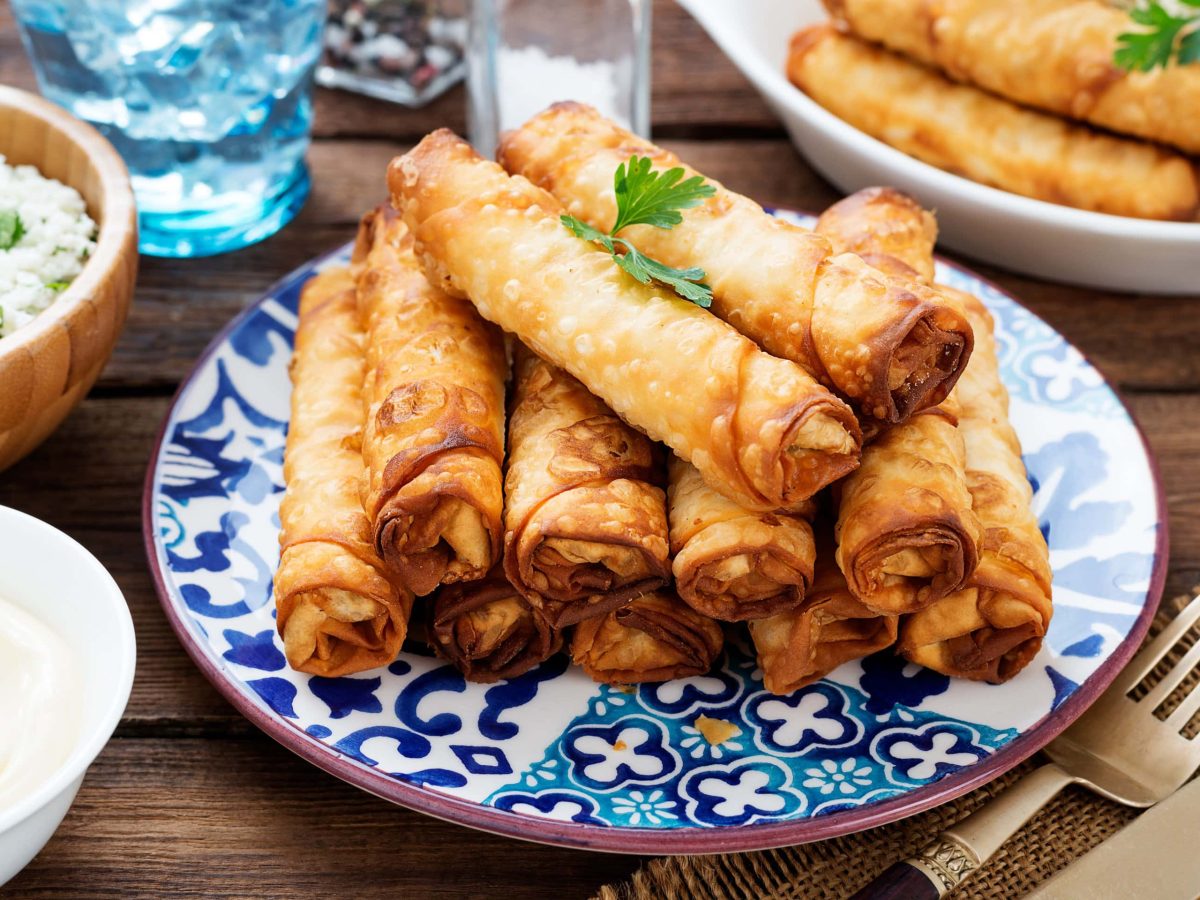 Auf einem otientalich anmutenden Teller lieben mehrere Börek mit Spinat-Feta-Fuellung.