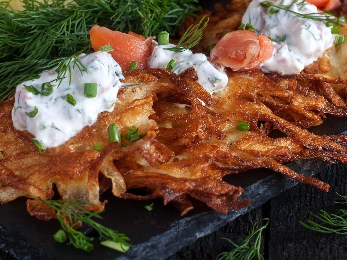 Kartoffelpuffer mit Lachs und Estragonquark, umringt von frischen Dillzweigen.