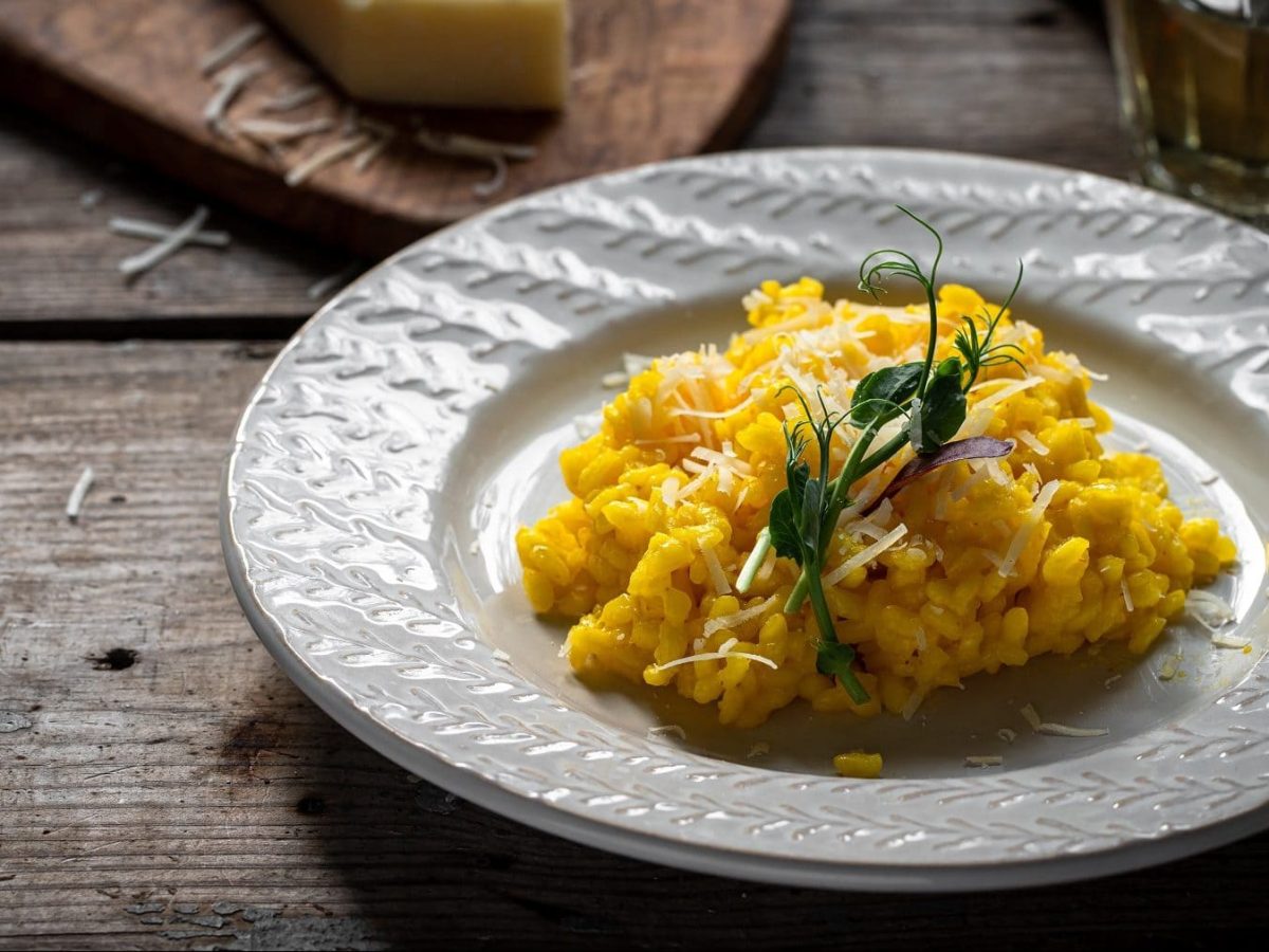 Auf einem weißen Teller ist Reis zu sehen. es handelt sich um ein Risotto alla milanese