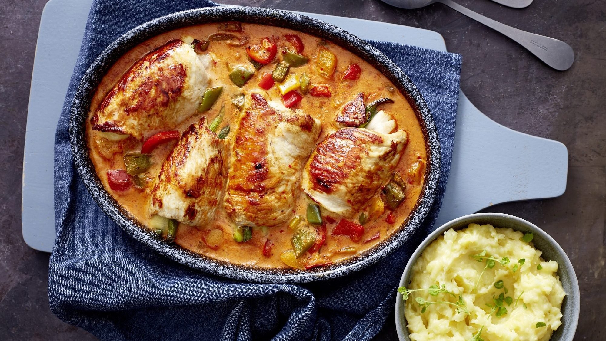 In einem großen Bräter sind Putenrouladen in Paprika-Sahne-Sauce. Daneben steht eine Schale mit Kartoffelpüree.